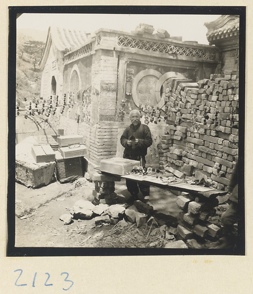 Man selling souvenirs outside temple building on Miaofeng Mountain