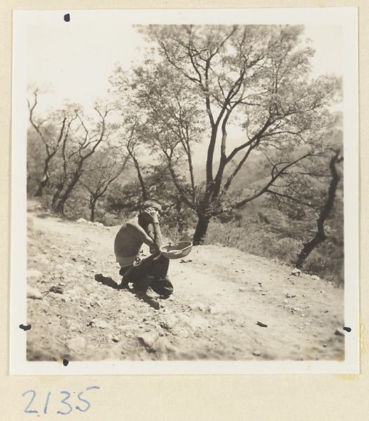 Seated man holding a basket on the pilgrimmage trail up Miaofeng Mountain