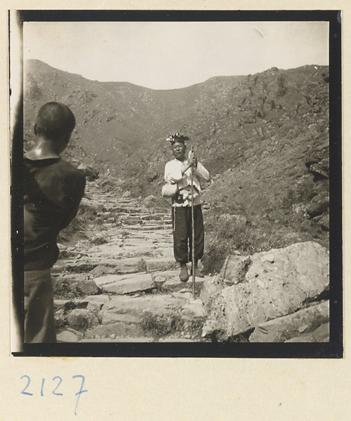 Pilgrim with souvenir hat and peach-wood walking stick descending Miaofeng Mountain