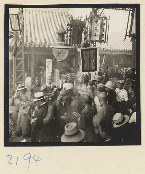 Pilgrims standing under lanterns holding burning incense in courtyard on Miaofeng Mountain