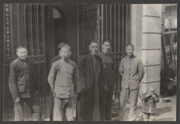 Men and boys in front of iron gate