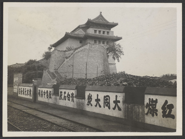 Fortified tower, wall with advertising, and railroad tracks