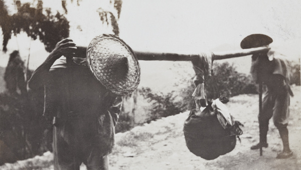 Two porters carrying a bundle on a bamboo pole