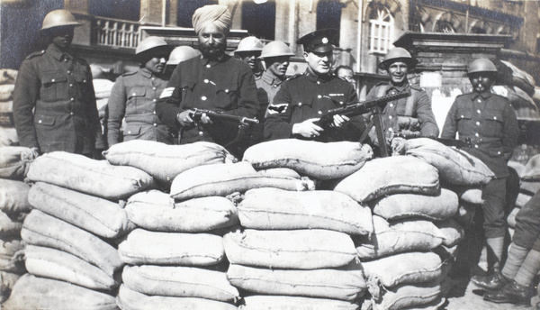 Shanghai Municipal Police posing with guns and soldiers, at a sandbagged guard post