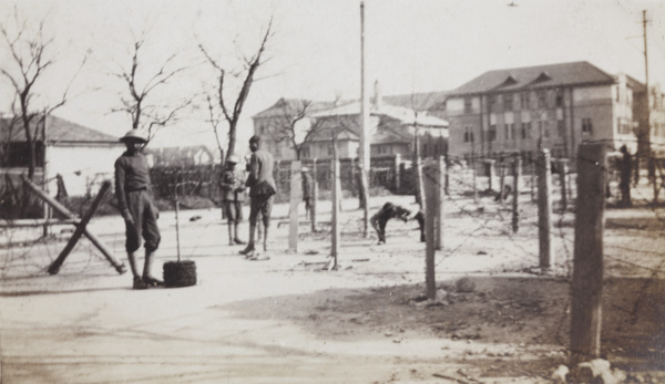 Soldiers by barbed wire entanglements at a road junction, Shanghai