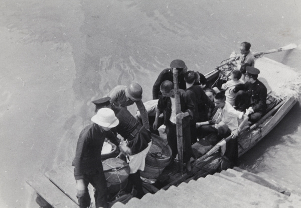 A boat with containers (likely food), a soldier, policemen, and others, by steps, Shanghai, 1937