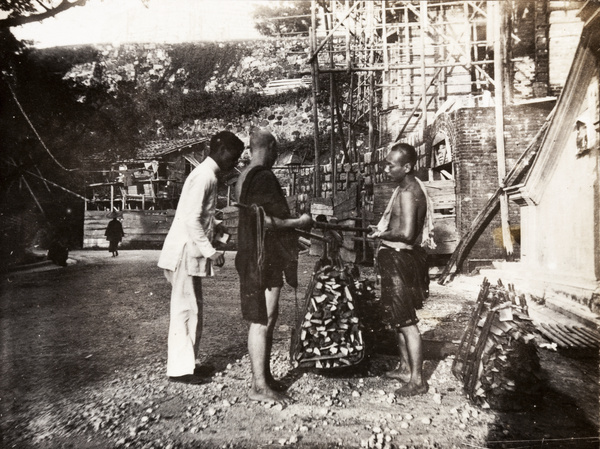 An overseer weighing loads of wood, by a building site, Hong Kong