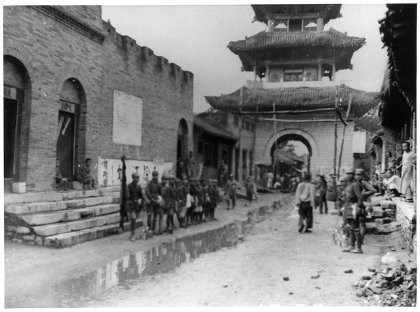 Soldiers in a street near a gateway