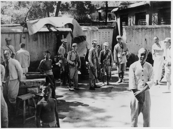 A group of soldiers, with civilians and children