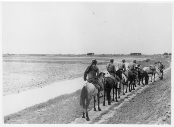 Chinese soldiers on horseback in single file on a track