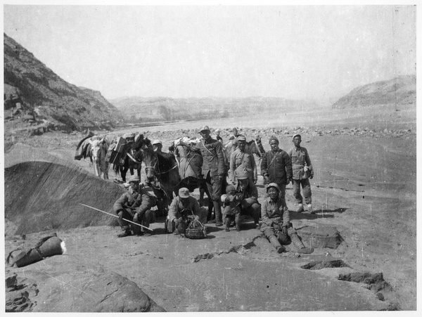 Soldiers with mules near a dried up river bed