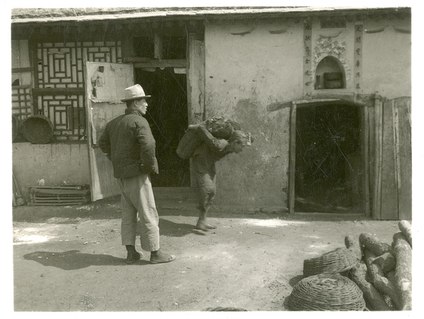 A worker carrying a sack of coal on his back out of a small coal mine