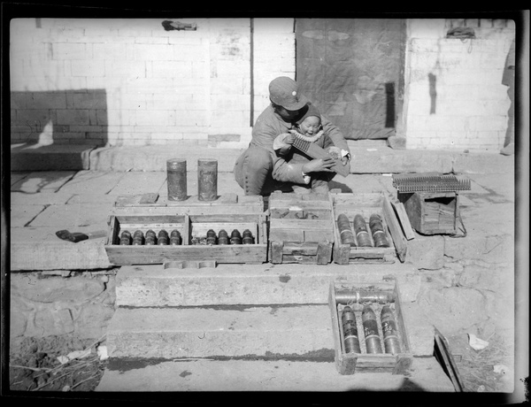 Erica Lindsay playing with machine gun cartridges, with 2nd Sub-district Chief of Staff and captured Japanese munitions, Jinchaji