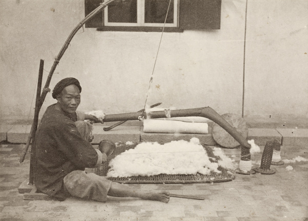 A man carding wool, posed with his tools