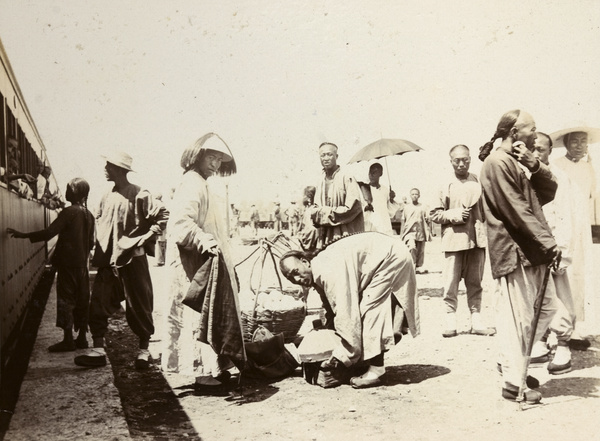 Chinese peddlar and other men at railway station