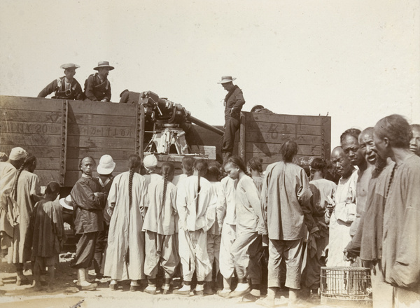 Ordnance loaded onto a railway truck, with onlookers