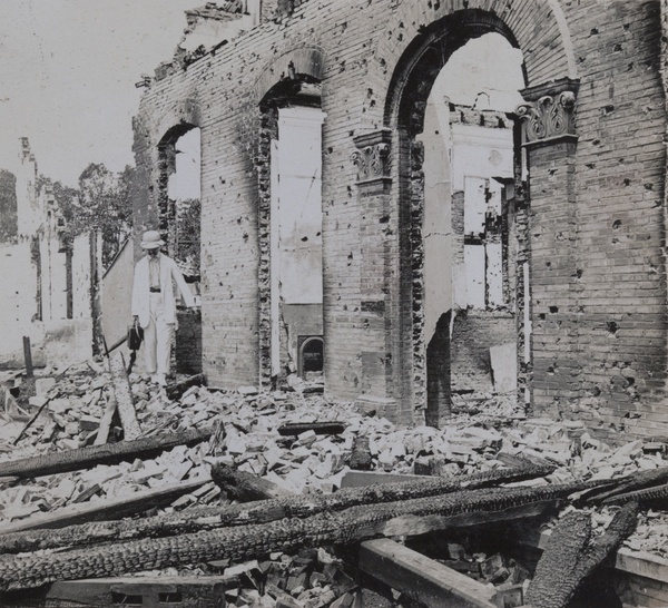 Man by the remains of a burnt down building