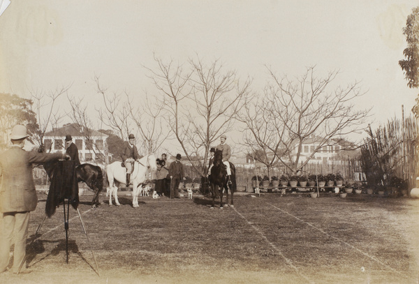 Photographing men on horseback, on a tennis court