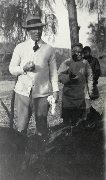 A man wearing a cardigan, with two other men