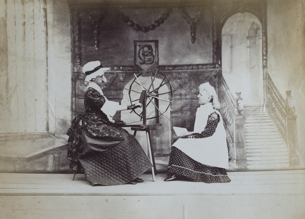 Two characters on stage, with a spinning wheel