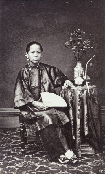 Portrait of a woman, with a fan, vase of flowers and a pipe