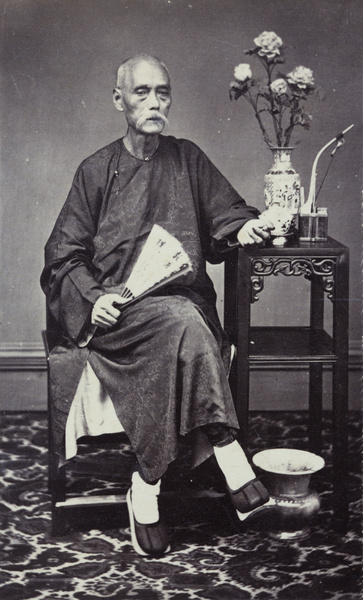 Portrait of an elderly man, with a fan, pipe, flowers and spittoon