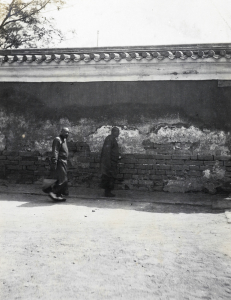 Priests walking in the shade by a wall, Beijing