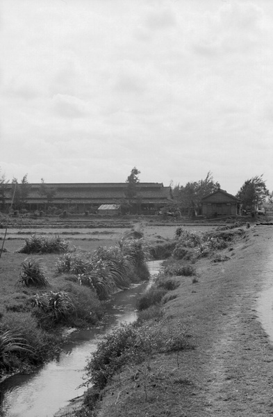 Ditch and fields by a large shed