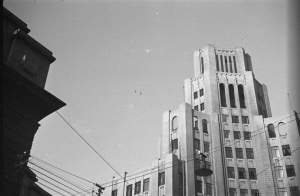 Two airplanes flying high above Metropole Hotel, Shanghai