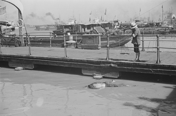 A man looking at a corpse in the Huangpu River, Shanghai