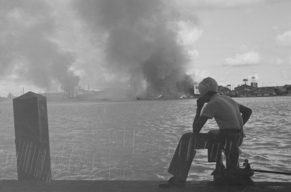 Sikh man looking over the river towards fires in Pudong, Shanghai