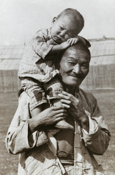 A smiling Chinese man with a boy perched on his shoulder