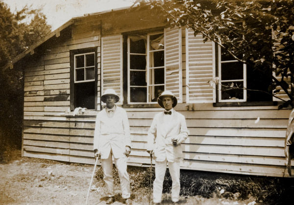 John Sullivan and unidentified man outside clapboard building