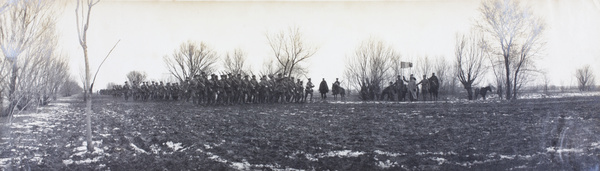 Soldiers marching along muddy route, past French Tricoleur flag, China