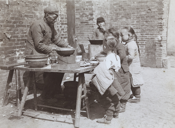 Cook and hot food stall, with young customers