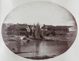 Houses by a river and stacks of bamboo