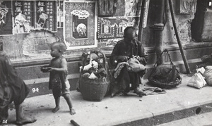 Pavement scene: a seamstress sewing and a toddler begging, Hong Kong