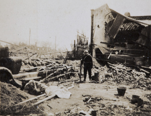 Japanese soldier standing by the wreckage of a bus, Shanghai, 1932