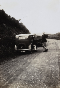 Two men and two cars parked at the side of a road