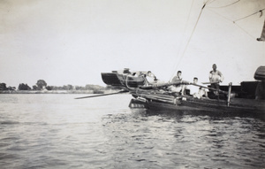 A boat with a tender on its stern, and oars
