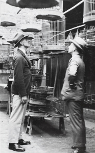 Two men looking at a bird cage