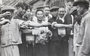 Young men showing off forearms pierced by hooks, with onlookers