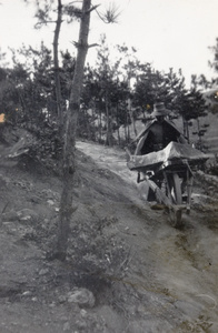 A carter with a large stone on a wheelbarrow