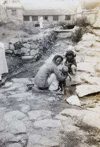 A woman with two children by a stream