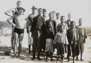 Royal Navy sailors, with children, on a beach