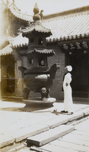 A Royal Navy sailor looking at an incense burner in a temple, Yantai (煙台)