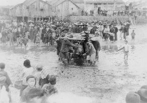 People in a fishing village watching men carrying the wayward torpedo