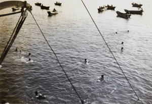 Royal Navy sailors swimming near their ship