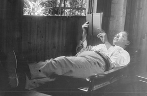 Sun Ke reading on a wooden chaise longue