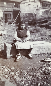 A young woman sitting on a stone slab at a vacant building plot